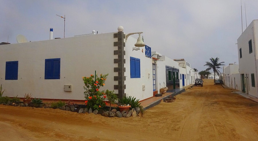 Calle de arena en Caleta de Sebo, con casas blancas de ventanas azules